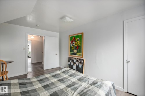 Bedroom featuring neutral tone walls, wood-finish flooring, a white flush-mount ceiling light, and white interior doors - 11022 110 Avenue, Edmonton, AB 