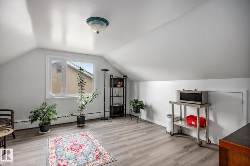 Bright space featuring sloped ceilings, a large window, wood-finish flooring, and a flush-mount ceiling light fixture - 11022 110 Avenue, Edmonton, AB 