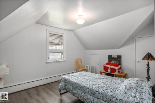 Attic room featuring sloped ceilings, a single window, baseboard heating, wood-finish flooring, and a flush-mount ceiling light - 11022 110 Avenue, Edmonton, AB 