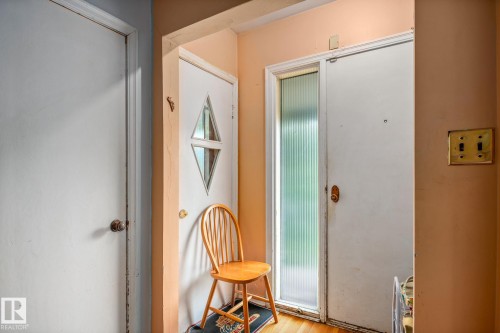 Entryway featuring a white door with a diamond-shaped window, a second white door with an opaque glass panel, and light wood-finish flooring - 11022 110 Avenue, Edmonton, AB 