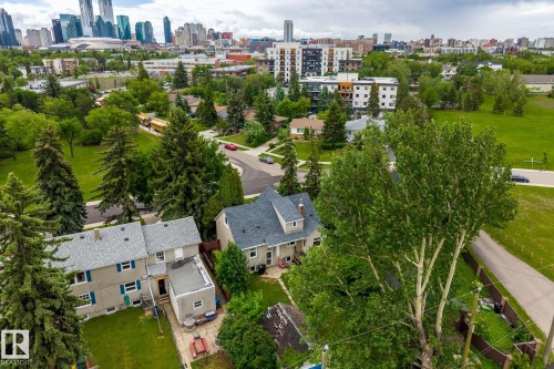 Aerial perspective showcasing a residential area with varied housing styles, mature trees, and urban skyline backdrop - 11022 110 Avenue, Edmonton, AB 