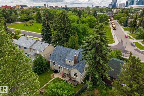 Bungalow-style residence featuring a gray shingle roof, a prominent brick chimney, and a front porch with railing - 11022 110 Avenue, Edmonton, AB 