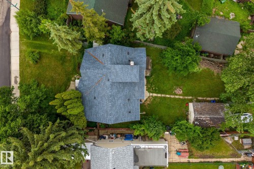 Property featuring a shingle roof, chimney, and surrounding green landscaping - 11022 110 Avenue, Edmonton, AB 