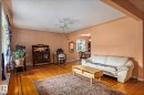 Spacious living area featuring wood-finish flooring, a ceiling fan, and large windows - 11022 110 Avenue, Edmonton, AB 