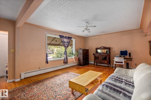Spacious room featuring wood-finish flooring, a large picture window, and a ceiling fan - 11022 110 Avenue, Edmonton, AB 