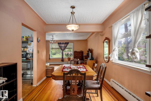 Dining area featuring wood-finish flooring with accent inlay, a ceiling-mounted light fixture, and a window with white trim - 11022 110 Avenue, Edmonton, AB 