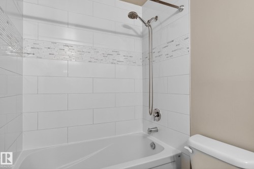 Bathtub and shower combination featuring white subway tile surround with a decorative mosaic accent band - 15112 80 Street, Edmonton, AB 
