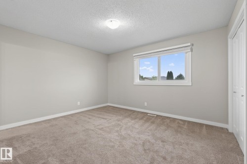 Bright interior space featuring neutral wall paint, textured ceiling, and a large window with white trim - 15112 80 Street, Edmonton, AB 