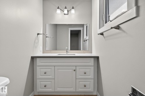 Bathroom vanity with integrated sink, dark countertop, and brushed nickel hardware - 15112 80 Street, Edmonton, AB 