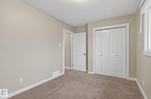 Neutral-toned room featuring light beige walls and a textured ceiling - 15112 80 Street, Edmonton, AB 