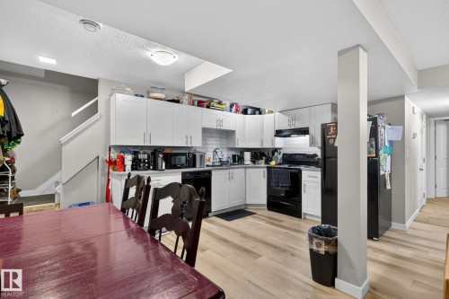 Kitchen featuring white cabinetry, light wood-finish flooring, a white subway tile backsplash, and black appliances - 15112 80 Street, Edmonton, AB 