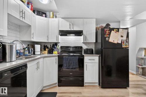 Kitchen featuring white shaker-style cabinetry, subway tile backsplash, and light-toned countertops - 15112 80 Street, Edmonton, AB 