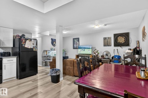 Open concept living area featuring wood-finish flooring, white walls, recessed lighting, and a partial kitchen with white cabinetry - 15112 80 Street, Edmonton, AB 