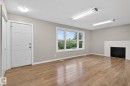 Bright room featuring wood-finish flooring, a white brick fireplace, and a large window - 15112 80 Street, Edmonton, AB 