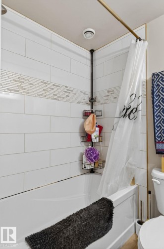 White subway tile shower surround featuring a decorative mosaic accent band and an integrated bathtub - 15112 80 Street, Edmonton, AB 