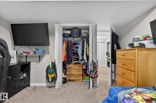 Carpeted interior room featuring a built-in closet with double doors, white wall paint, and a wall-mounted shelf - 15112 80 Street, Edmonton, AB 