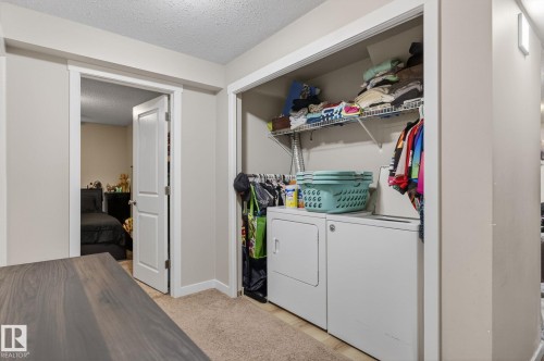 Dedicated laundry area featuring a washer and dryer, wire shelving, and hanging rod - 15112 80 Street, Edmonton, AB 