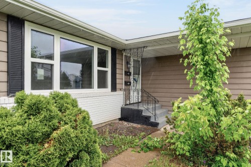 Exterior featuring horizontal siding, white brick foundation, large picture windows with white framing, and black shutters - 15112 80 Street, Edmonton, AB 