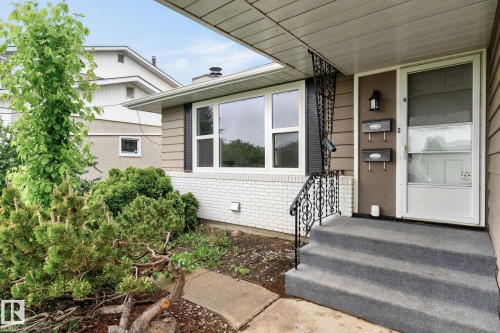 Front entry featuring a screen door, exterior light fixture, and wrought iron handrail - 15112 80 Street, Edmonton, AB 