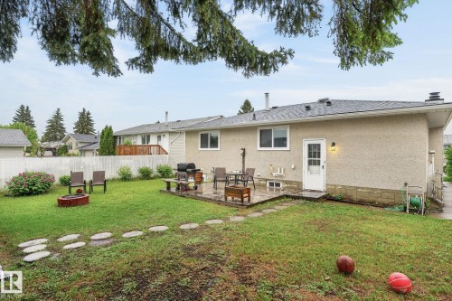 Spacious backyard featuring a stone patio, mature landscaping, and a white picket fence - 15112 80 Street, Edmonton, AB 