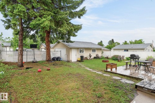Expansive backyard featuring a wood deck, stone pathway, and mature trees - 15112 80 Street, Edmonton, AB 