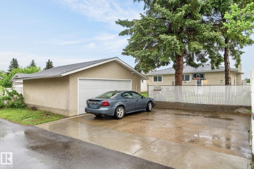 Detached garage with a pitched shingle roof, stucco exterior, and a single-panel garage door - 15112 80 Street, Edmonton, AB 