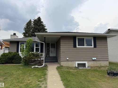 Ranch-style exterior featuring horizontal siding in a neutral tone, white window frames with dark shutters, and a gray shingle roof - 15112 80 Street, Edmonton, AB 