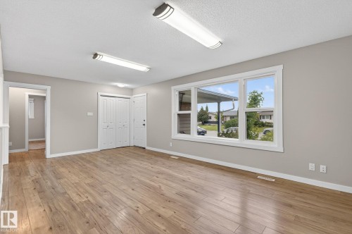 Spacious interior room featuring wood-finish flooring, neutral wall paint, and white trim - 15112 80 Street, Edmonton, AB 