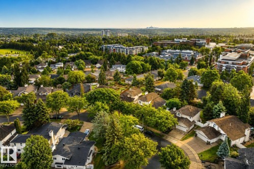 Aerial perspective showcasing a residential neighborhood with a mix of single-family homes and multi-story buildings, featuring abundant mature trees and curving street layouts - 9 Emerald Terrace, St. Albert, AB 