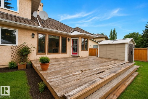 Rear exterior featuring a large wood deck with multiple steps, a beige stucco facade, and a brown shingle roof - 9 Emerald Terrace, St. Albert, AB 