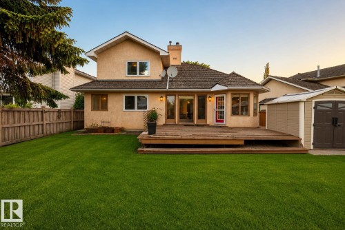 Expansive green lawn with a wooden privacy fence, a multi-level wood deck, and a detached storage shed - 9 Emerald Terrace, St. Albert, AB 