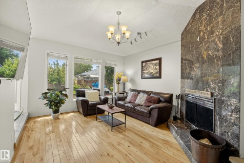 Living area featuring hardwood flooring, a vaulted ceiling, and an ornate chandelier - 9 Emerald Terrace, St. Albert, AB 