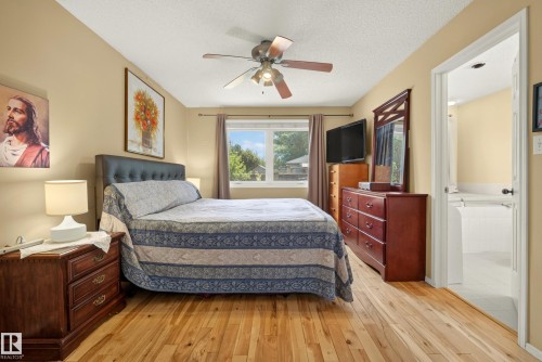 Spacious room featuring wood-finish flooring, a ceiling fan, and a large window with outdoor views - 9 Emerald Terrace, St. Albert, AB 