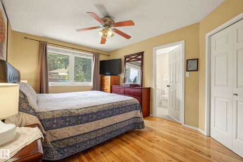 Hardwood flooring throughout featuring a ceiling fan with integrated lighting, a large window, and two bi-fold closet doors - 9 Emerald Terrace, St. Albert, AB 