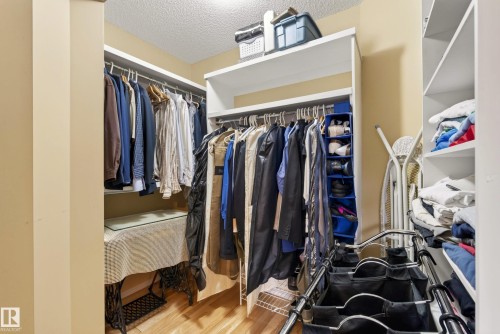 Walk-in closet featuring wood-finish flooring, built-in shelving, and hanging rods - 9 Emerald Terrace, St. Albert, AB 