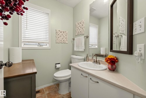 Bathroom featuring a vanity with an integrated sink, a large wall mirror, and a window with horizontal blinds - 9 Emerald Terrace, St. Albert, AB 