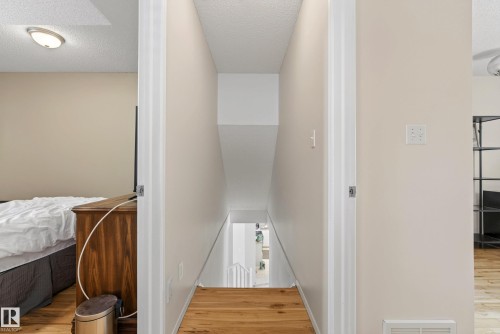 Hallway featuring wood-finish flooring, light neutral wall tones, white trim, and a staircase with white railings - 9 Emerald Terrace, St. Albert, AB 
