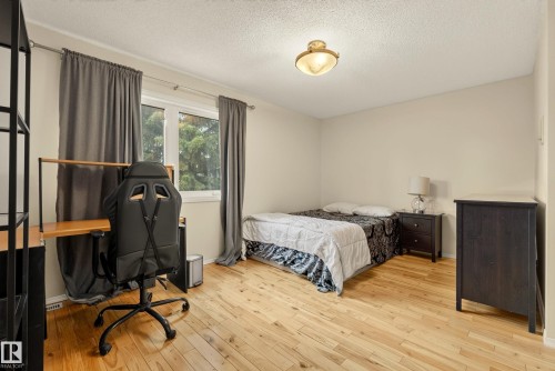 Bedroom featuring light wood-finish flooring, neutral wall paint, a large window with drapes, and a ceiling-mounted light fixture - 9 Emerald Terrace, St. Albert, AB 