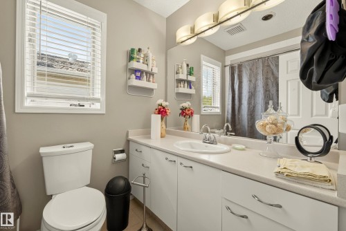 Bathroom featuring a single vanity with a white countertop, an undermount sink, and a large mirror - 9 Emerald Terrace, St. Albert, AB 