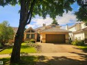 Stucco exterior residence featuring a prominent front-facing garage with a brown door - 9 Emerald Terrace, St. Albert, AB 