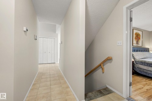 Hallway featuring neutral wall tones, tile flooring, and a bi-fold closet door - 9 Emerald Terrace, St. Albert, AB 