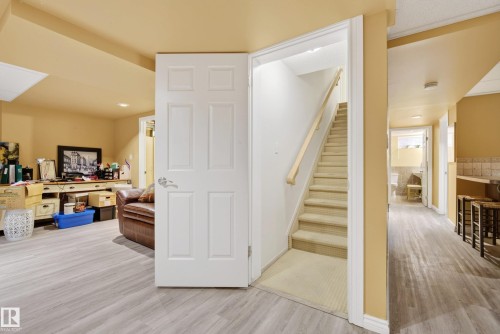Lower level featuring wood-finish flooring, a six-panel interior door, and a staircase with carpeted treads and a wood handrail - 9 Emerald Terrace, St. Albert, AB 