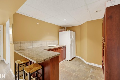 Compact kitchen area featuring a built-in wood-finish cabinet system with a laminate countertop and tiled backsplash - 9 Emerald Terrace, St. Albert, AB 