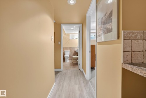 Hallway with wood-finish flooring, recessed lighting, and access to a bathroom featuring tiled walls and a toilet - 9 Emerald Terrace, St. Albert, AB 