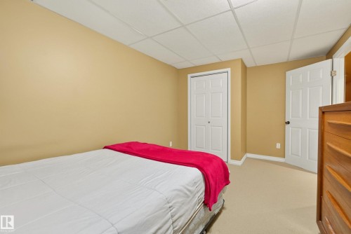 Bedroom featuring neutral-toned walls, light-colored carpeting, and a white bi-fold closet - 9 Emerald Terrace, St. Albert, AB 
