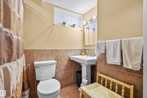 Bathroom featuring a pedestal sink, white toilet, and a medicine cabinet with integrated lighting - 9 Emerald Terrace, St. Albert, AB 