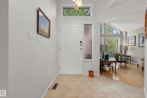 Entryway featuring a paneled door with a frosted sidelight and transom window, tile flooring, and wood-finish flooring - 9 Emerald Terrace, St. Albert, AB 