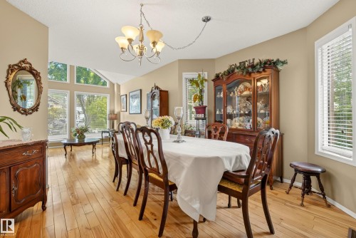 Dining area featuring polished wood-finish flooring, a multi-light chandelier, and expansive windows - 9 Emerald Terrace, St. Albert, AB 