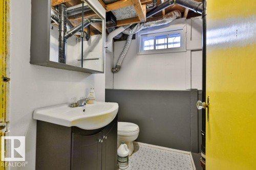 Compact bathroom featuring a white vanity sink, dark wood-finish cabinetry, and an overhead mirrored medicine cabinet - 8318 80 Avenue, Edmonton, AB 