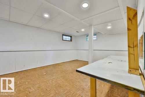 Finished basement area featuring recessed lighting, a drop ceiling, wood-finish flooring, and white paneled walls - 8318 80 Avenue, Edmonton, AB 